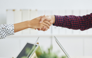 Women shaking hands over laptop