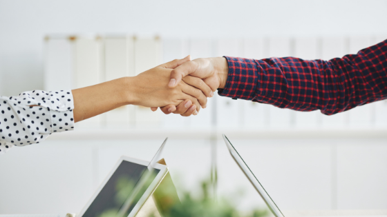 Women shaking hands over laptop