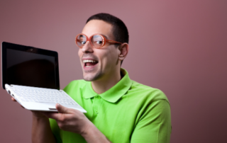Guy with red glasses and green shirt holding laptop