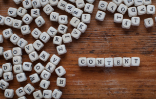 The word content spelled by letter blocks in the right corner, with other block letters spread out around it on a wooden background