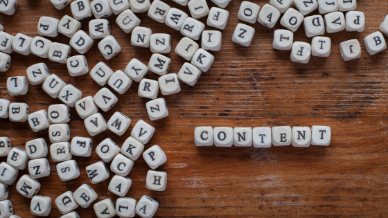 The word content spelled by letter blocks in the right corner, with other block letters spread out around it on a wooden background